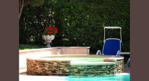 a swimming pool with a blue chair and a vase with red flowers at Hotel D&eacute;sir&eacute;e - Garda Lake Collection in Sirmione