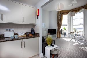 una cucina con armadi bianchi e un soggiorno di Sea-la-vie, Astor House a Torquay