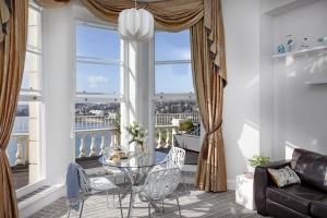 un soggiorno con tavolo in vetro e sedie di fronte a una finestra di Sea-la-vie, Astor House a Torquay