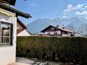 una casa con un seto delante de una casa en Kleines Häuschen mit Bergblick, en Eschenlohe