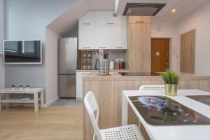 a kitchen with white cabinets and a table and chairs at Urban Jungle Apartment in the city center in Białystok