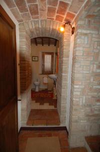 a hallway leading to a bathroom with a stone wall at La Capanna di Panpepato in Rosia