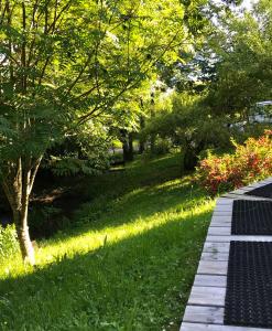 a park with a lawn with trees and a sidewalk at Gîte Le Mazot de Vouan in Saint-André-de-Boëge