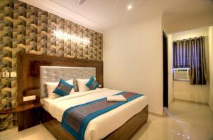 a bedroom with a large bed with blue pillows at Hotel Ark Avalon- Delhi International Airport in New Delhi