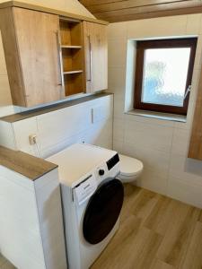 a small bathroom with a toilet and a washing machine at Kleines Häuschen mit Bergblick in Eschenlohe