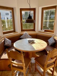 a dining room with a table and chairs and windows at Kleines Häuschen mit Bergblick in Eschenlohe