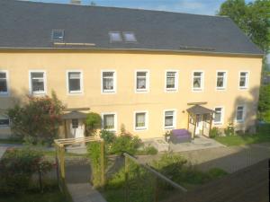 un gran edificio amarillo con un parque infantil delante de él en Ferienwohnung Am Lindenbaum, en Kirnitzschtal