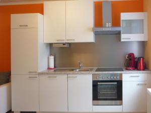 eine Küche mit weißen Schränken und einem Waschbecken in der Unterkunft Ferienwohnung Am Lindenbaum in Kirnitzschtal