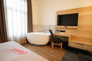 a bathroom with a tub and a television and a bed at Hotel Restaurant Zur Linde in Westerstede