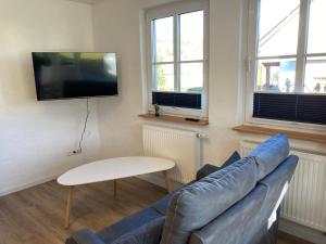 ein Wohnzimmer mit einem Sofa und einem TV an der Wand in der Unterkunft Ferienwohnung Zum Eifelelch in Daun