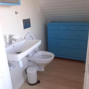 a bathroom with a sink and a toilet and a blue dresser at Belvedere B&B in Svendborg