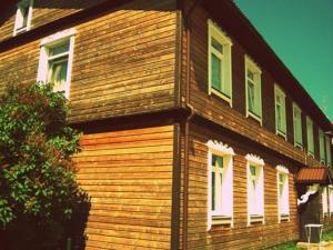 ein Holzhaus mit weißen Fenstern an der Seite in der Unterkunft Isabela Apartments in Palanga