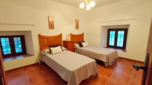 a bedroom with two beds and two windows at El Locutorio in San Martín de la Vega del Alberche