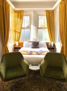 a bedroom with a bed and two green chairs at The Cedars Ashby in Ashby de la Zouch