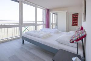 a bedroom with two beds and a large window at Kustverhuur, Appartement aan zee, Port Scaldis 05042 in Breskens