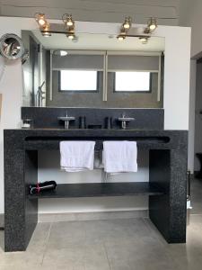 a bathroom with a black counter with two sinks and towels at 45BB Apartment in Carcassonne +14 photos