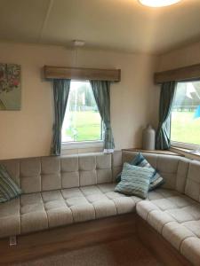 a couch in a living room with two windows at Lovely 3-Bed Caravan with Hot Tub in Lincolnshire in Lincoln