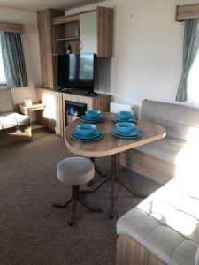 a living room with a table with blue dishes on it at Lovely 3-Bed Caravan with Hot Tub in Lincolnshire in Lincoln