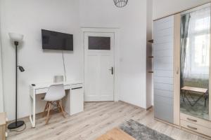 a white room with a desk and a tv on the wall at Apartament Mesa - NoclegiSopot in Sopot