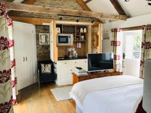 a bedroom with a bed and a tv in a room at The Old Dairy Retreat in St Austell