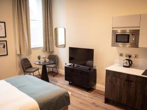 a hotel room with a bed and a flat screen tv at The Gresham Aparthotel in Leicester