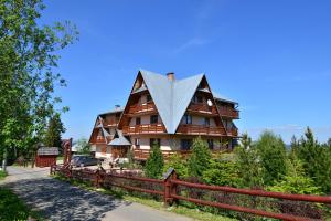 een groot houten huis met een schilddak bij Miś Pokoje Gościnne in Bukowina Tatrzańska