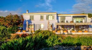 a large white house with people sitting on the patio at Villa Pischinas in Magomadas