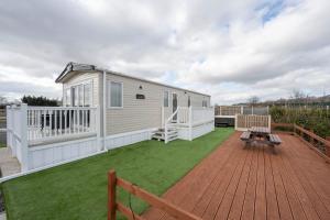 a mobile home with a deck and grass at Hallcroft Fishery And Holiday Park in Retford