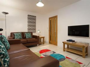 a living room with a couch and a flat screen tv at Bakery Cottage - Lake District in Bowness-on-Windermere