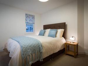 a bedroom with a bed and a table with a lamp at Bakery Cottage - Lake District in Bowness-on-Windermere