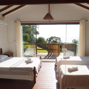 a room with three beds and a large window at Morada Sunset Praia do Rosa in Praia do Rosa