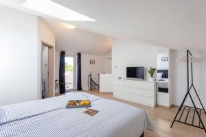 een witte slaapkamer met een bed en een televisie bij Apartments Punta Premantura in Premantura