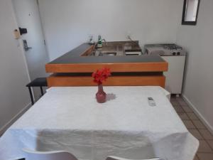 a kitchen with a table with a vase with a red flower at Flat no la residence com acesso a clube in Vitória