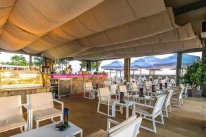 a restaurant with white chairs and tables and a bar at Mobile Home Pag near Pebble Beach & Pools in Novalja
