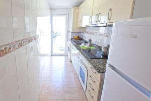 a white kitchen with a refrigerator and a tile floor at APCOSTAS Villa de Madrid in Blanes