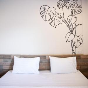 a bedroom with a bed with a flower stencil on the wall at Tree Home ที่พักเบตงสไตล์ครอบครัว in Ban Komo Sip Paet