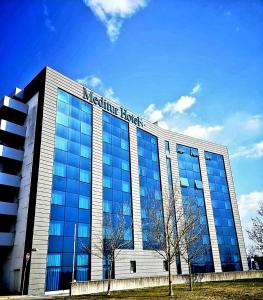 un gran edificio de cristal con un cartel. en Meditur Hotel Udine Nord, en Udine