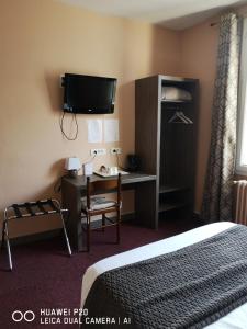 a hotel room with a bed and a desk and a tv at Hôtel Le Memphis in Poitiers