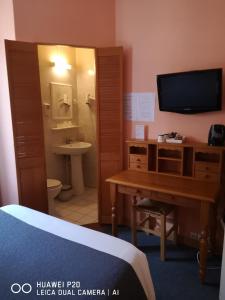 a room with a desk and a bathroom with a television at Hôtel Le Memphis in Poitiers