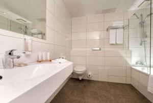 a white bathroom with a sink and a toilet at Wyndham Köln in Cologne