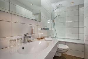 a white bathroom with a sink and a toilet at Wyndham Köln in Cologne