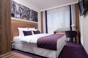 a bedroom with a bed and a desk and a window at Wyndham Köln in Cologne