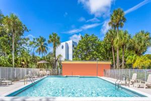 uma piscina com cadeiras e palmeiras em Days Inn by Wyndham Fort Lauderdale Airport Cruise Port em Fort Lauderdale