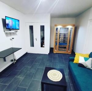 ein Wohnzimmer mit einem Sofa, einem Tisch und einem TV in der Unterkunft Suite Perla - Balnéo et Sauna in Le Mée-sur-Seine