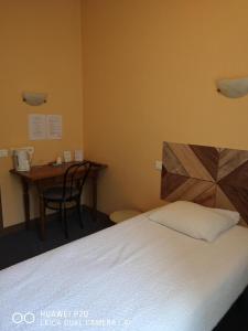 a bedroom with a bed and a desk and a table at Hôtel Le Memphis in Poitiers