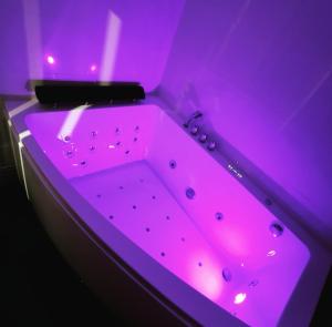 eine Badewanne mit violetter Beleuchtung in einem Zimmer in der Unterkunft Suite Perla - Balnéo et Sauna in Le Mée-sur-Seine
