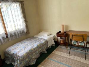 a bedroom with a bed and a desk and a table at Guest House Wind Inn Hakuba in Hakuba