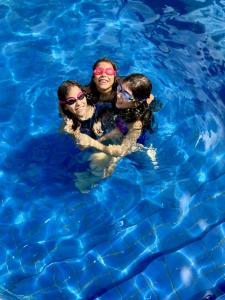 drie vrouwen in een zwembad met een hond bij Pousada Coqueiro Verde in Itacaré