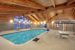 a swimming pool in a building with a table and an umbrella at AmericInn by Wyndham Sayre in Sayre