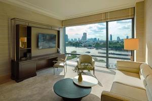 a living room with a couch and a large window at Capella Bangkok in Bangkok